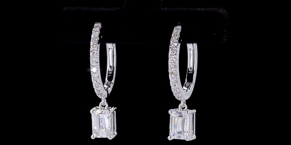 Pair of silver hoop earrings with Emerald cut diamond on a black background