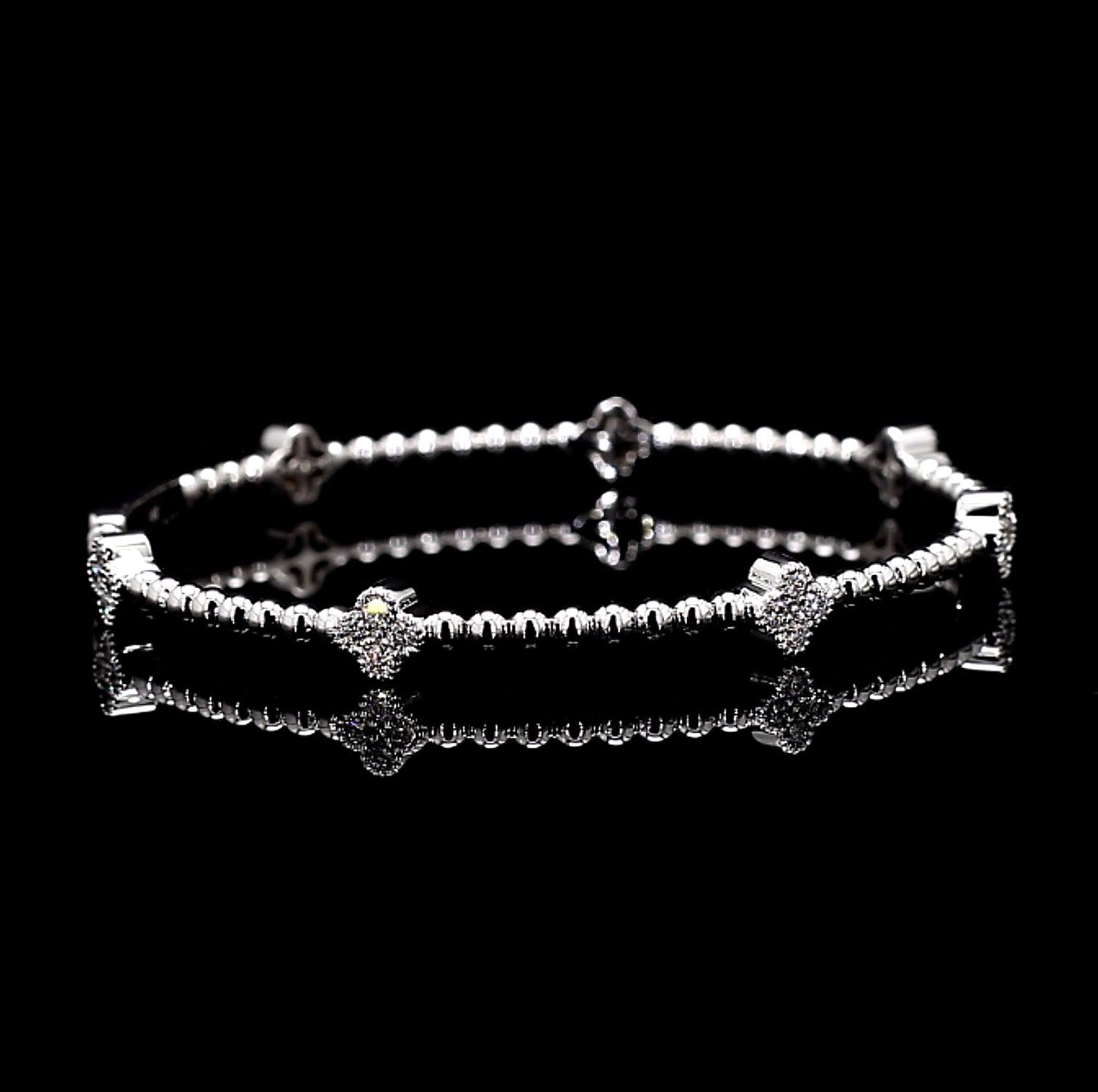 White Gold bracelet with clover charm star and bar designs on a black background