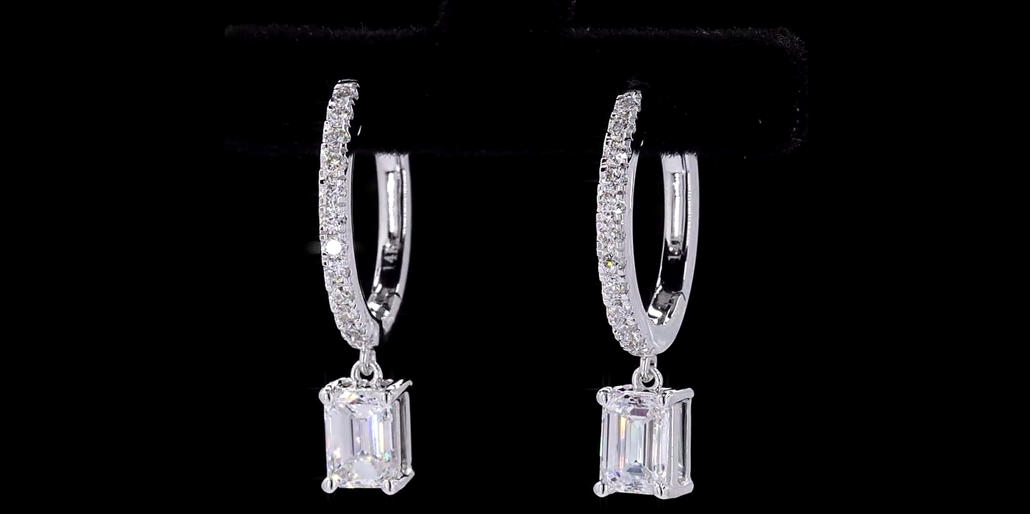 Pair of silver hoop earrings with Emerald cut diamond on a black background