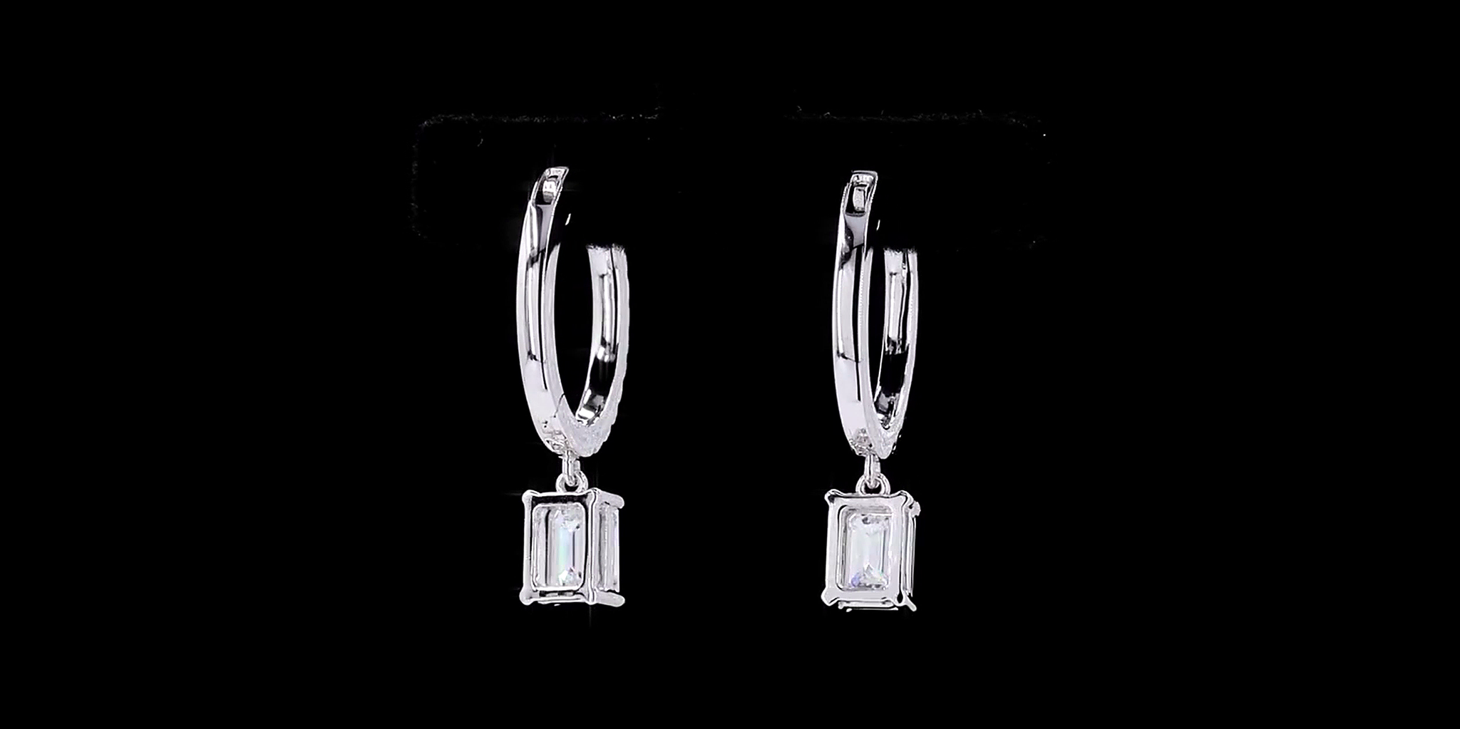 Pair of silver hoop earrings with Emerald cut diamond on a black background