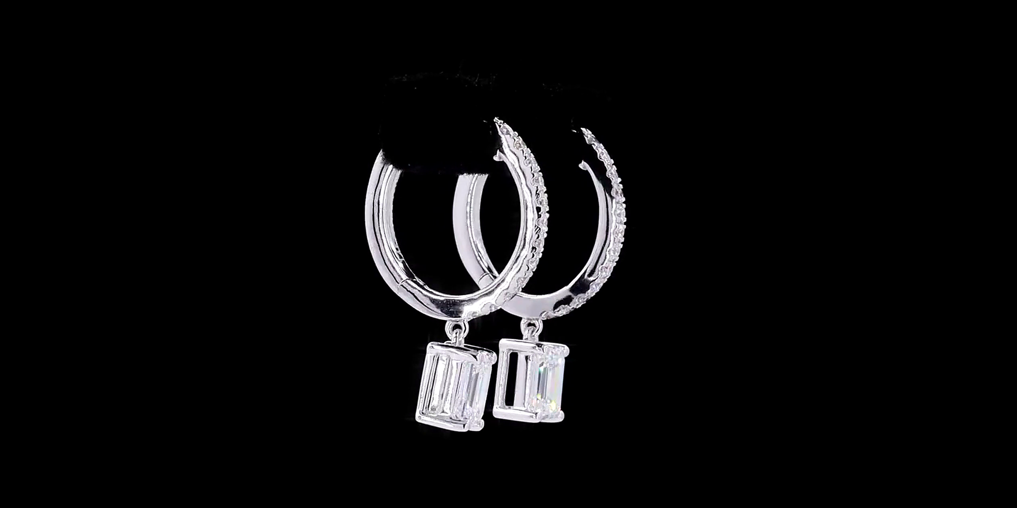 Pair of silver hoop earrings with Emerald cut diamond on a black background