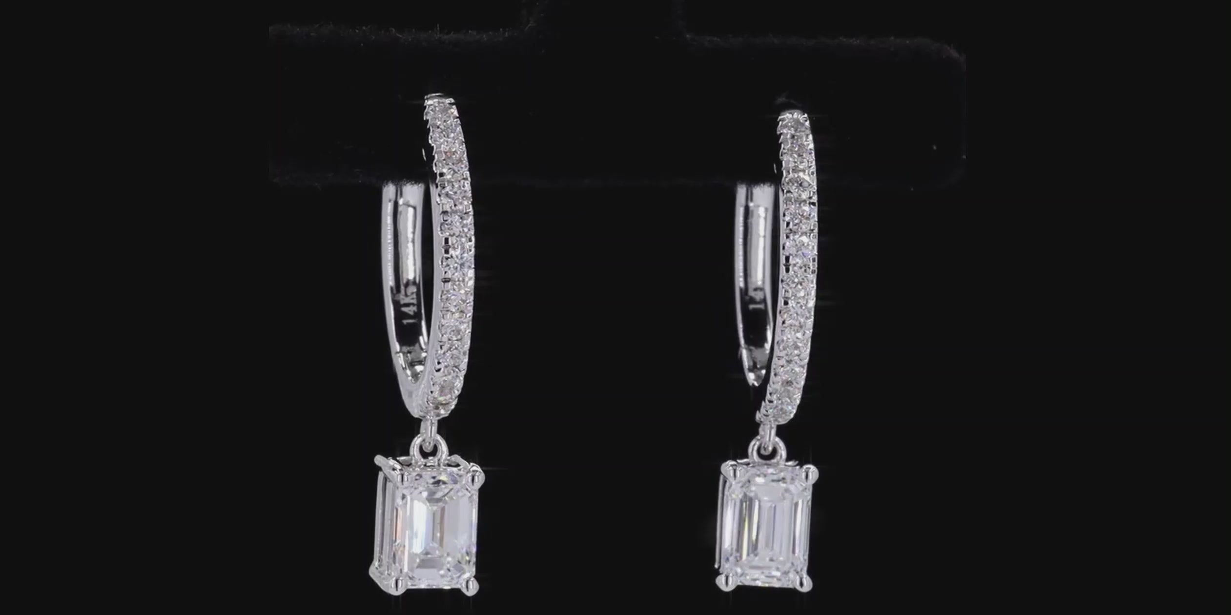 Pair of silver hoop earrings with Emerald cut diamond on a black background
